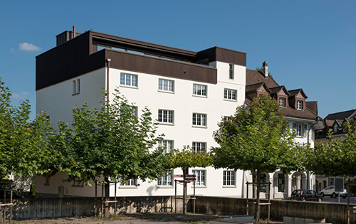 Un lé de façade coloré sous des plaques d’aluminium perforées, surélévation en construction bois